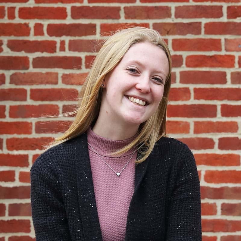 molly hudson headshot in front of brick wall